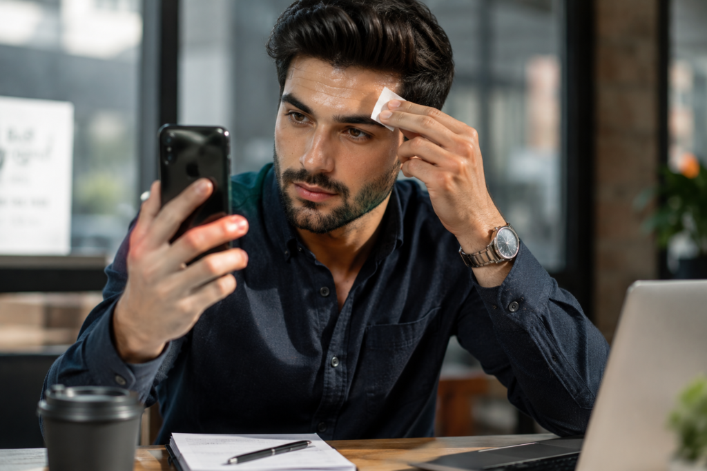 A man checking oily skin with blotting paper in a modern office setting
